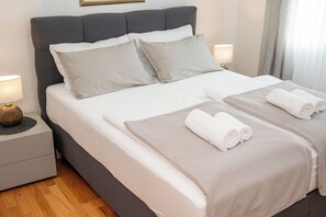 A neatly made bed with pillows and towels, a bedside lamp, and a nightstand. - Apartments Villa Ana (Fazana)