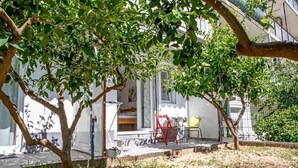 Een woonhuis met een overdekte veranda, een rode stoel en een kleine tafel.