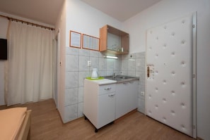A compact kitchen with a sink, a cabinet with a mirror, a small countertop, and a door with a lock. - Apartments Studio Spalato (Split)
