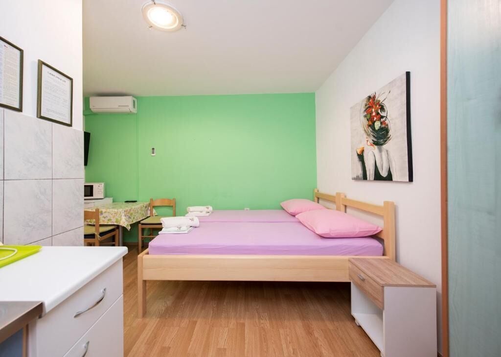 A small bedroom with a bed, a desk, a chair, and a microwave.
