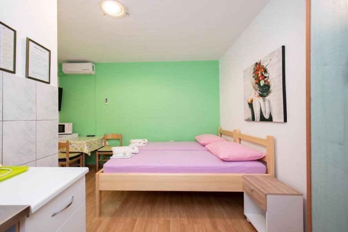 Pequeña habitación con cama, escritorio, silla y microondas.