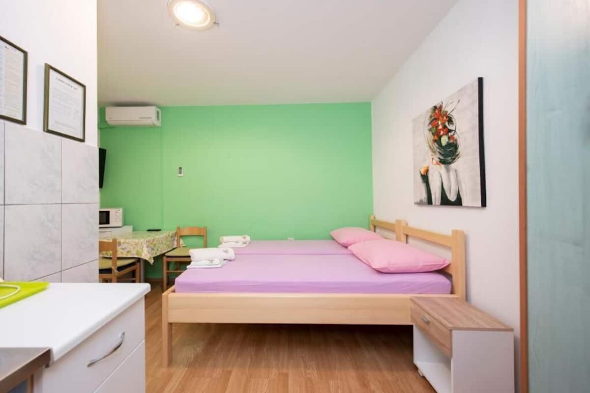 Une petite chambre avec un lit, un bureau, une chaise et un four à micro-ondes.