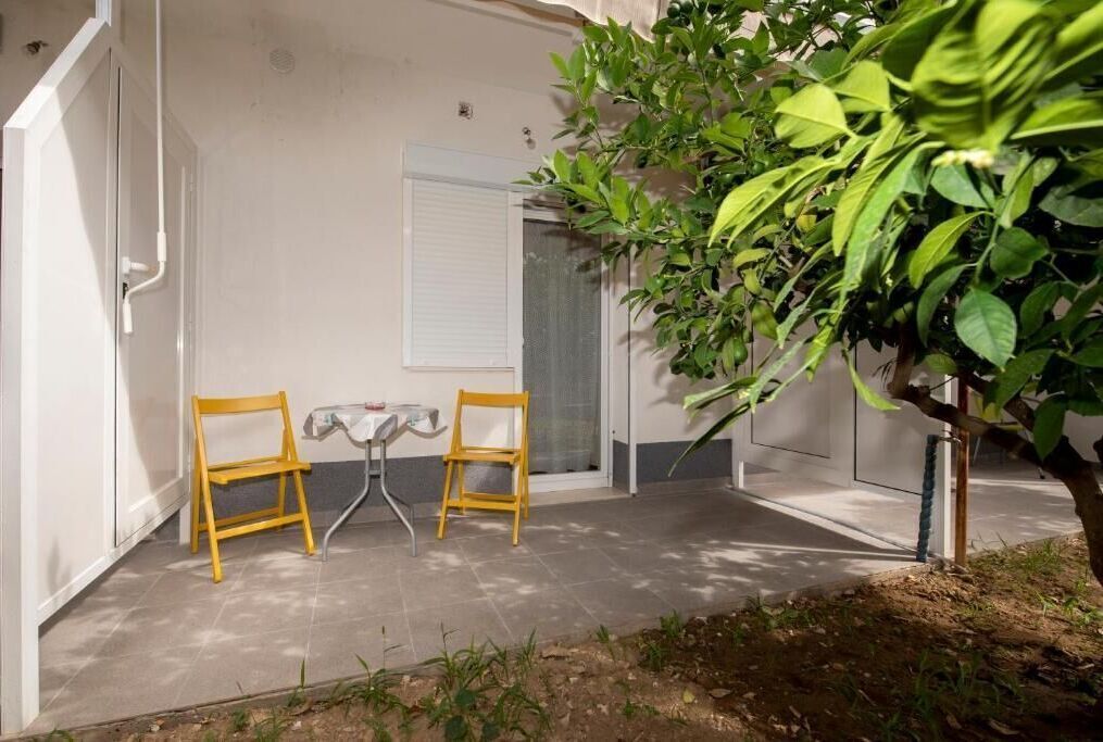 A patio area with two yellow chairs, a small table, and a potted plant.