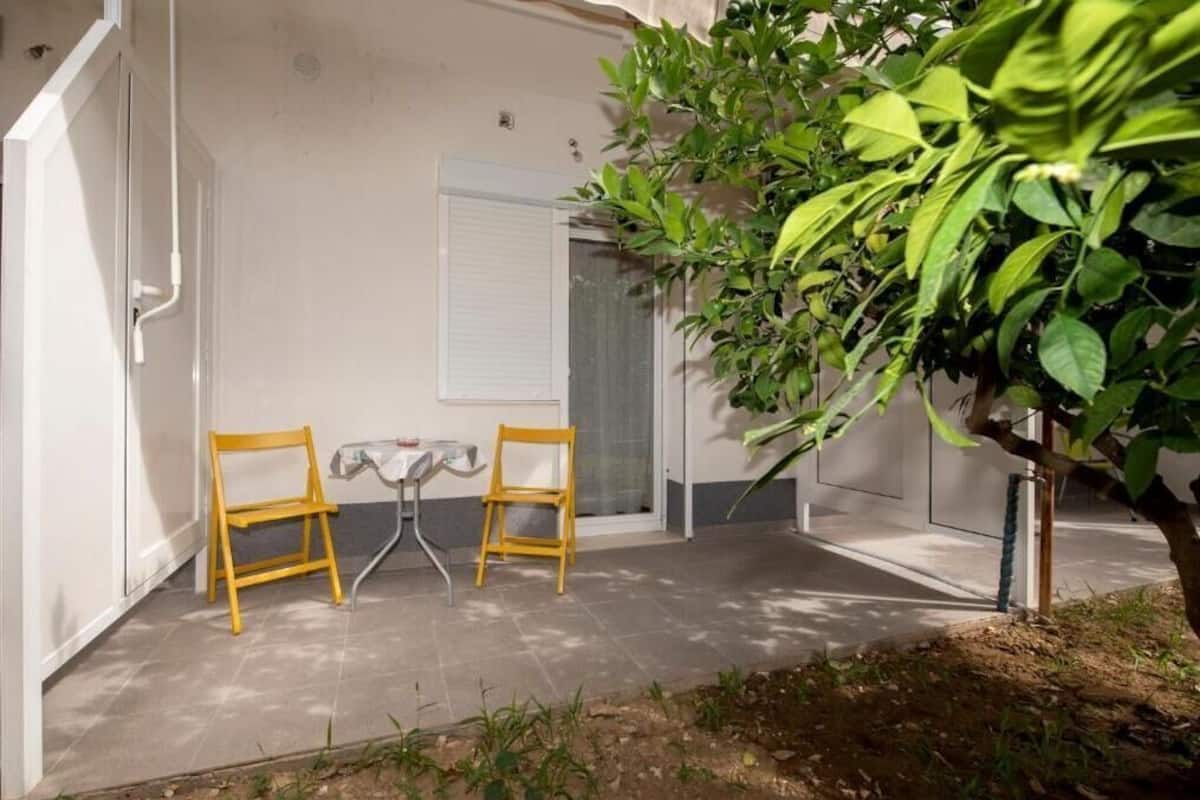 Un patio con dos sillas amarillas, una mesita y una planta en maceta.