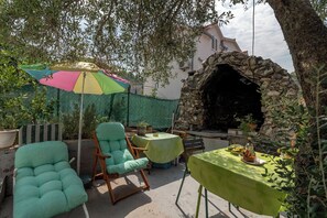 Eine Terrasse mit Sitzgelegenheit im Freien, einem steinernen Bogen und einem farbenfrohen Sonnenschirm.