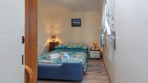 A narrow room with a bed, a nightstand, a lamp, and a picture on the wall. - Apartments Kate (Trogir)