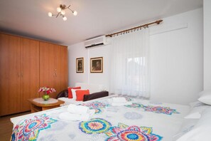 Ein Schlafzimmer mit einem Bett, einem Holzschrank, einem kleinen Tisch mit einer Vase und zwei gerahmten Bildern an der Wand.