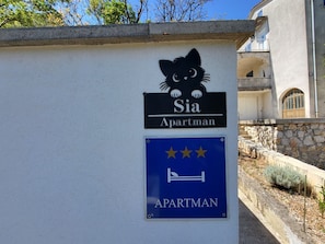 Una pared con dos carteles: uno con la silueta de un gato y el texto 'Sia Apartment', y otro con tres estrellas y el texto 'APARTMAN'.