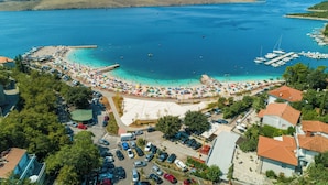 An aerial view of a coastal area with a beach, marina, and surrounding buildings. - Apartment Sia (Crikvenica)