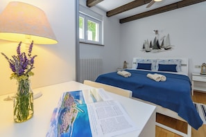 A bedroom with a bed, a lamp, a vase with flowers, and a window. - Apartment Kiara (Kraljevica)