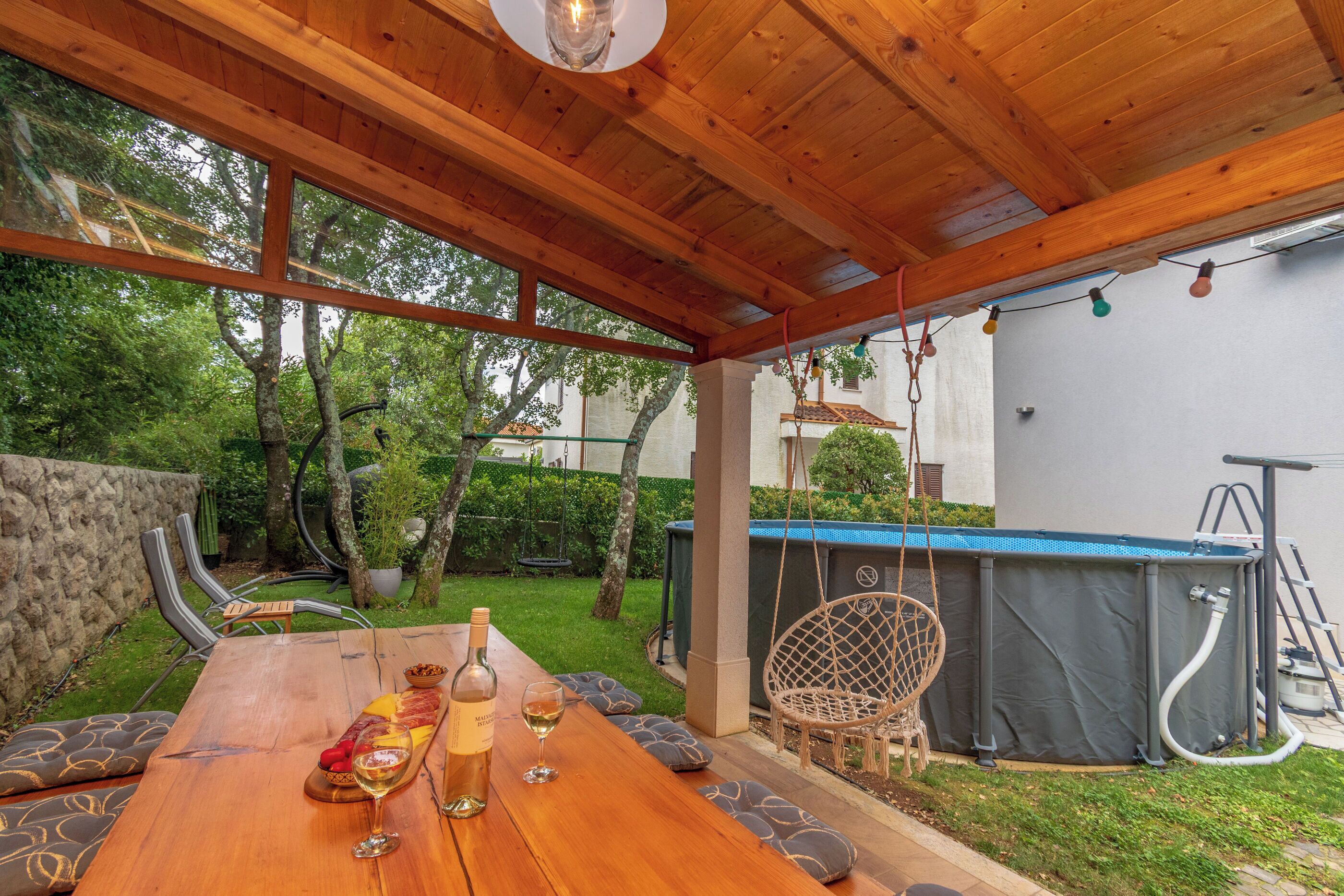 Una terraza de madera con una mesa dispuesta para comer, rodeada de sillas y cojines.