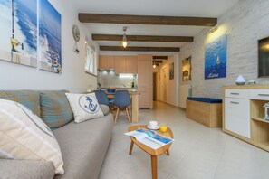 Uma sala de estar moderna com sofá, área de jantar, cozinha e vista para o mar.