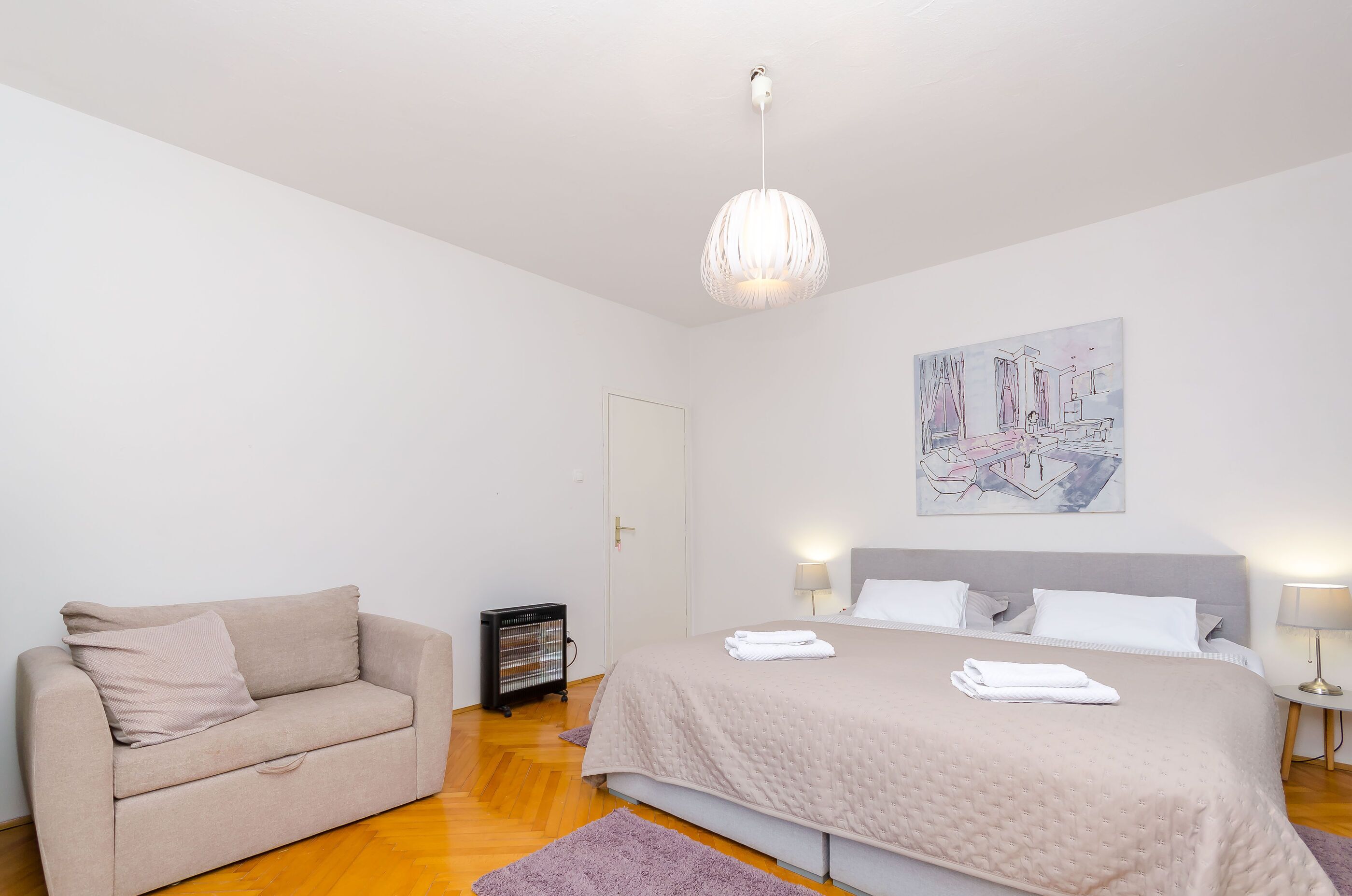 Ein Schlafzimmer mit einem Bett, einem Schlafsofa, einem Heizkörper, einem Gemälde und einer Lampe.