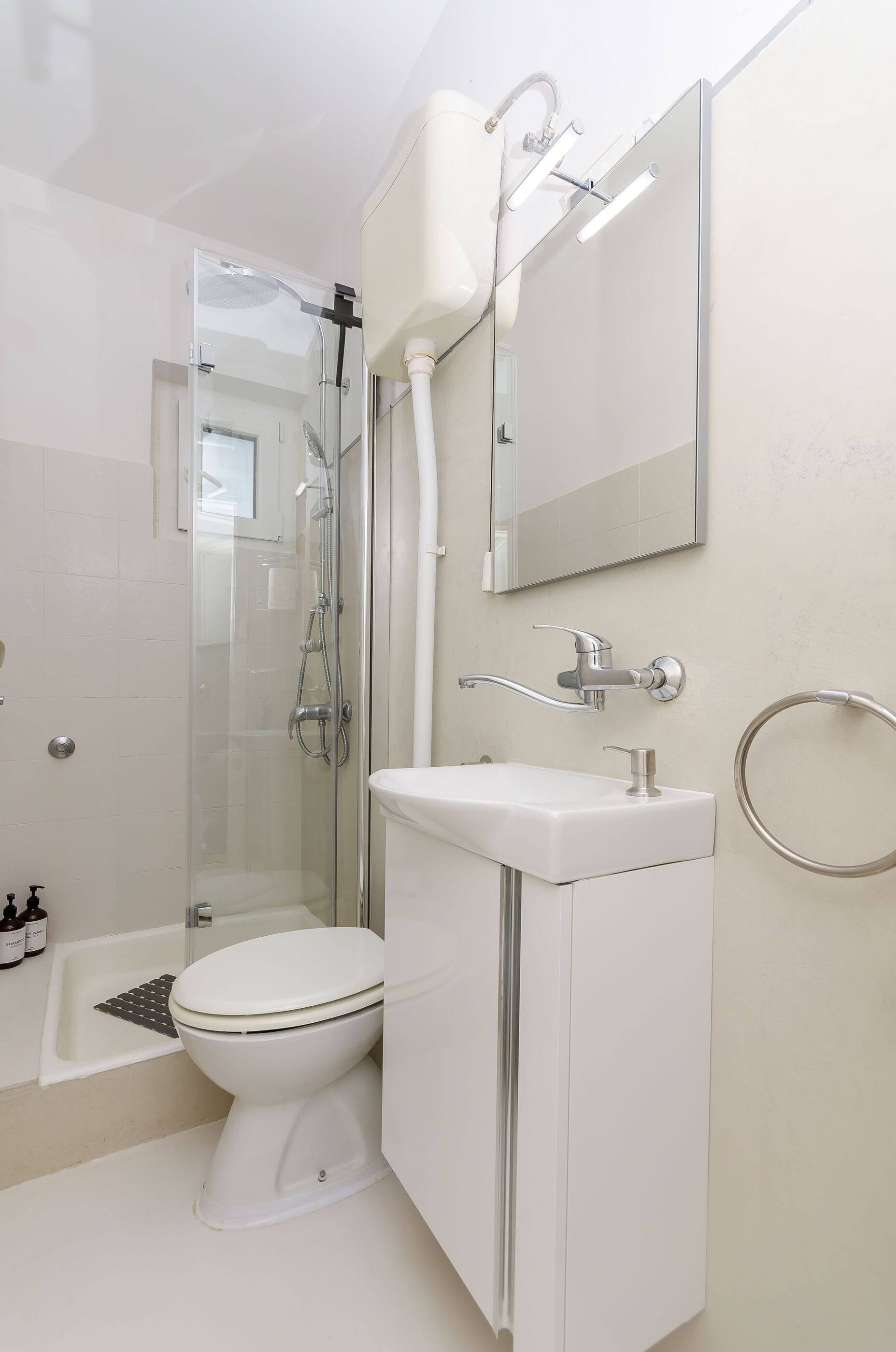 A bathroom with a toilet, sink, mirror, shower, and bathtub.