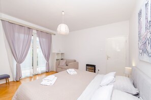 A bedroom with a bed, bedside table, lamp, and a view of the outdoors. - Apartments In Center (Jelsa)