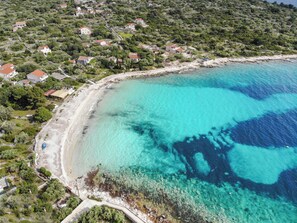 Eine Luftaufnahme einer Küstenregion mit Häusern, klarem türkisblauem Wasser und einem Sandstrand.