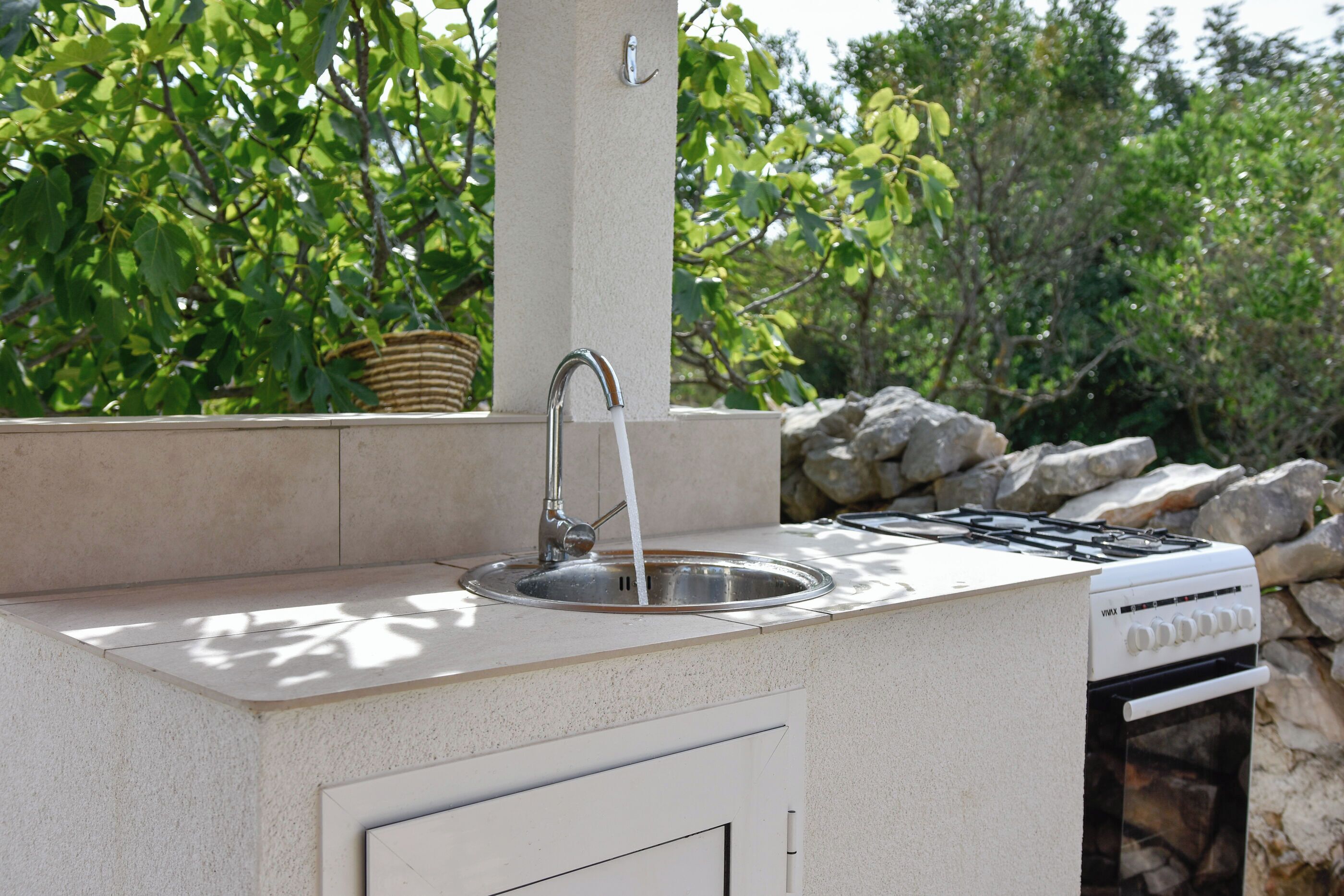 Cocina exterior con pileta, grifo y estufa.