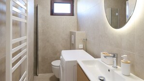 A modern bathroom with a toilet, sink, mirror, and a towel rack. - Apartments Andi (Sukosan)