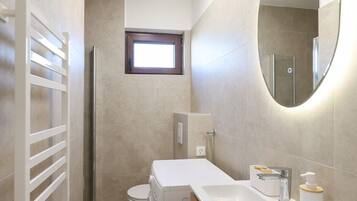 A modern bathroom with a toilet, sink, mirror, and a towel rack.