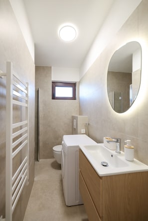 Ein modernes Badezimmer mit Toilette, Waschbecken, Spiegel und Handtuchhalter.