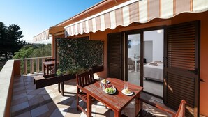A balcony with a table set for two, a chair, and a small garden area. - Apartments Andi (Sukosan)