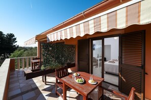 Ein Balkon mit Tisch für zwei Personen, einem Stuhl und einer kleinen Gartenanlage.