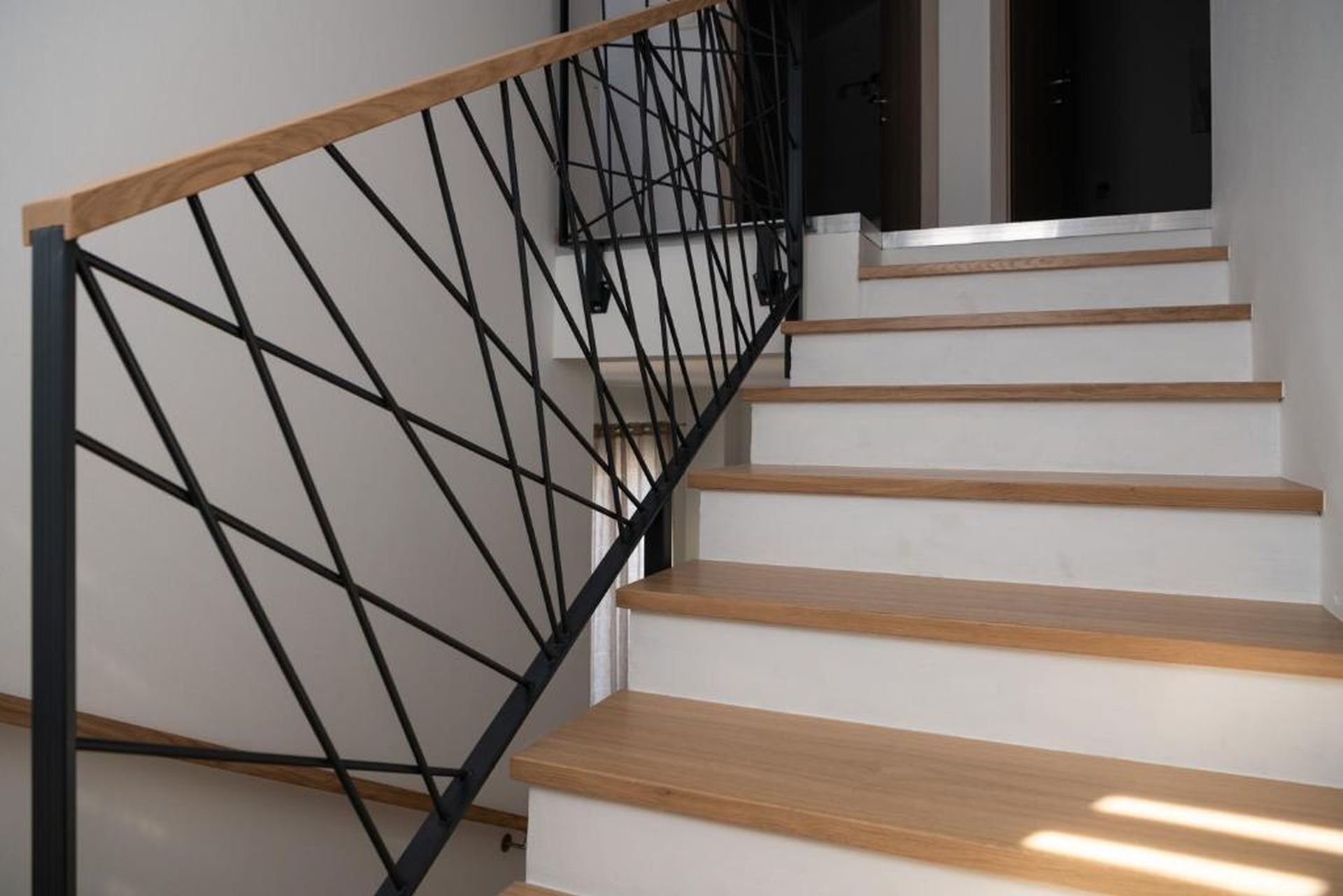 Un escalier avec des marches en bois et une rampe en métal noir.