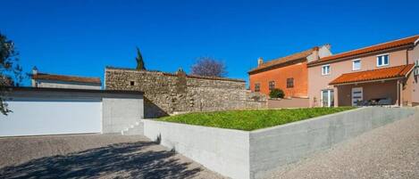 A residential area with a stone wall, a concrete retaining wall, and a building with a red roof.
