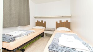 A room with two single beds, a small table, and a bench. - Mobile Home Fisherman (Pasman)