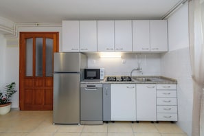 A compact kitchen with white cabinets, a stainless steel refrigerator, a microwave, a dishwasher, and a gas stove. - Apartment Aurora (Opatija)