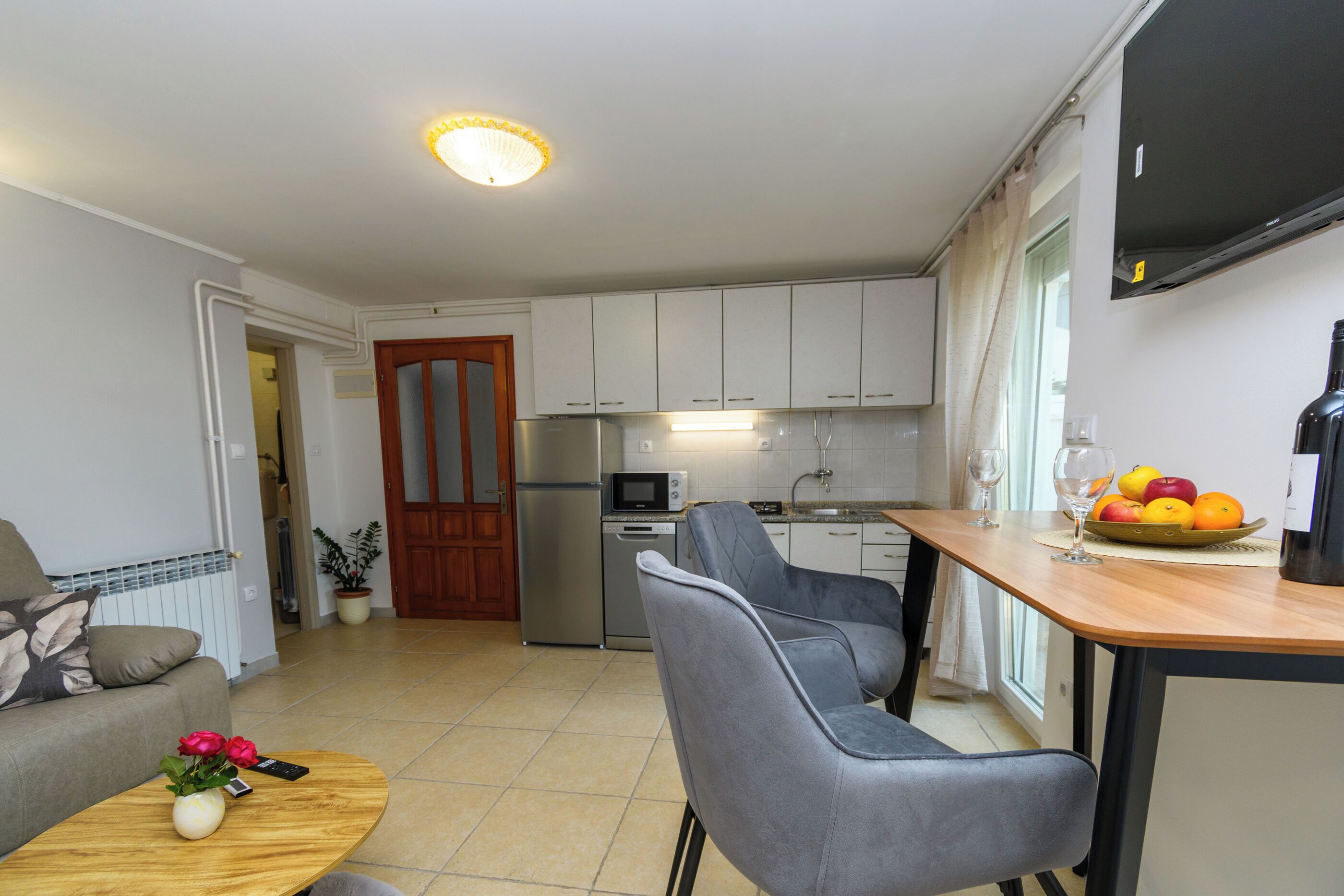 A compact living space with a kitchenette, a dining area with a table and chairs, and a sofa.