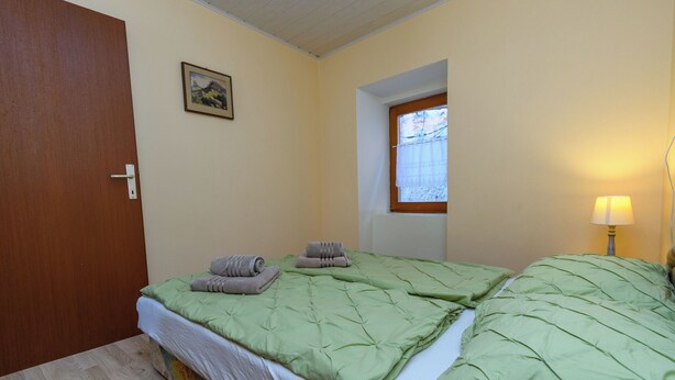 Una habitación con dos camas, una puerta, una ventana y un cuadro colgado en la pared.