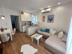 Ein modernes Wohnzimmer mit einer Couch, einem Couchtisch und einem Essbereich mit Tisch und Stühlen.