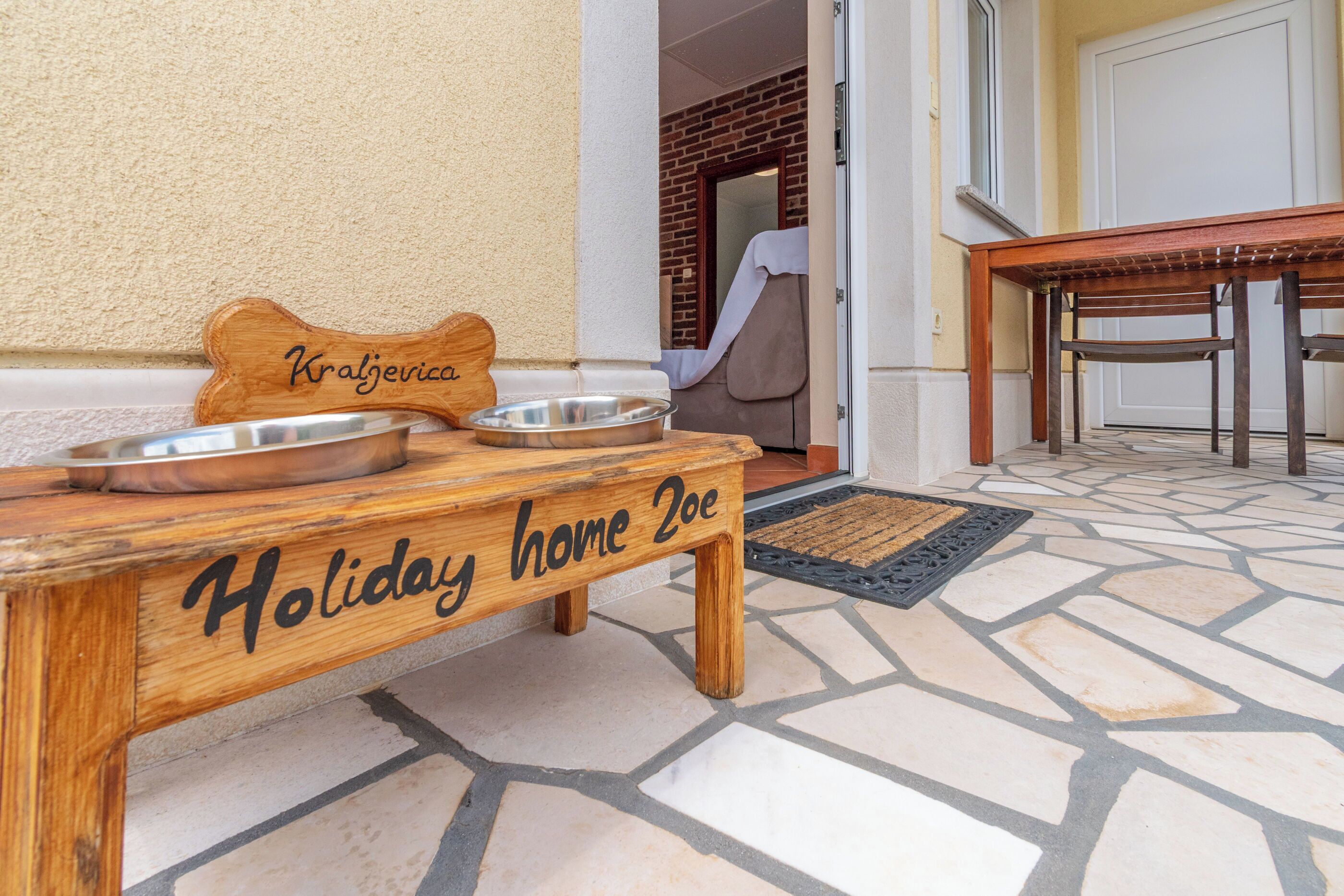 Un banco de madera con la etiqueta 'Holiday home 2oe', un cuenco metálico y un objeto con forma de hueso.