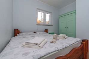 Ein Schlafzimmer mit einem Bett, einem Fenster, einer grünen Tür und einem Nachttisch.