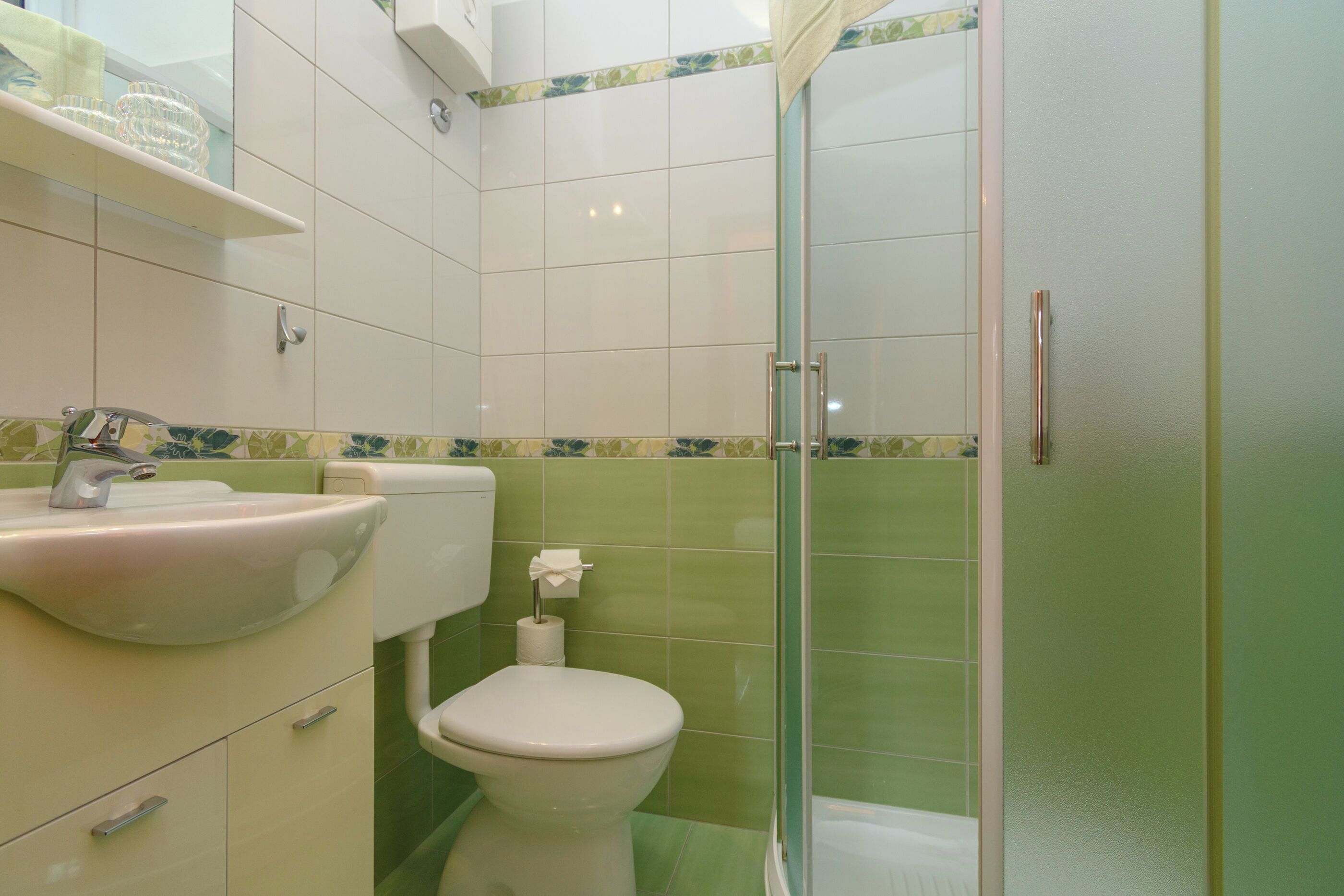 A bathroom with a sink, toilet, and glass shower enclosure.