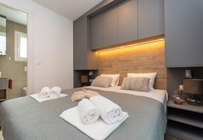 A modern hotel room with a large bed, two bedside tables, a wooden headboard, and a bathroom visible through an open door. - Mobile Home Oaza Mira Camping 111 (Pakostane)
