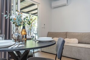 A dining area with a round table set for two, a sofa, and a vase with flowers. - Mobile Home Oaza Mira Camping 111 (Pakostane)