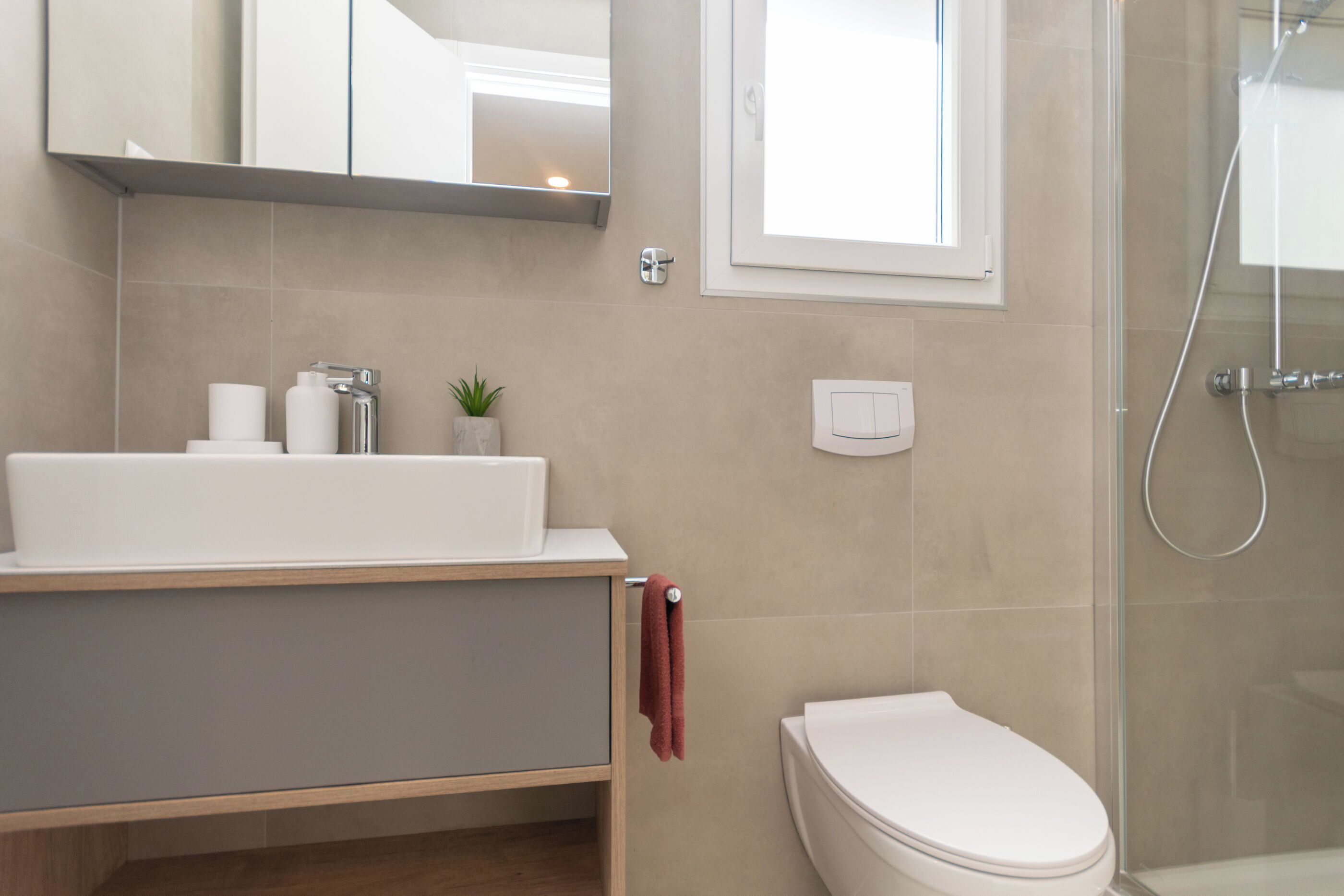 A bathroom with a toilet, sink, mirror, and shower.