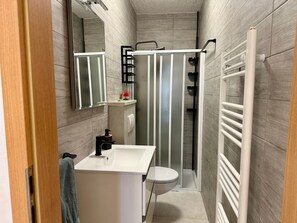 A modern bathroom with a white sink, mirror, and shower enclosure. - House House Lola (Rasa)