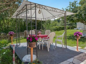 A gazebo with a table and chairs, surrounded by greenery. - House House Lola (Rasa)