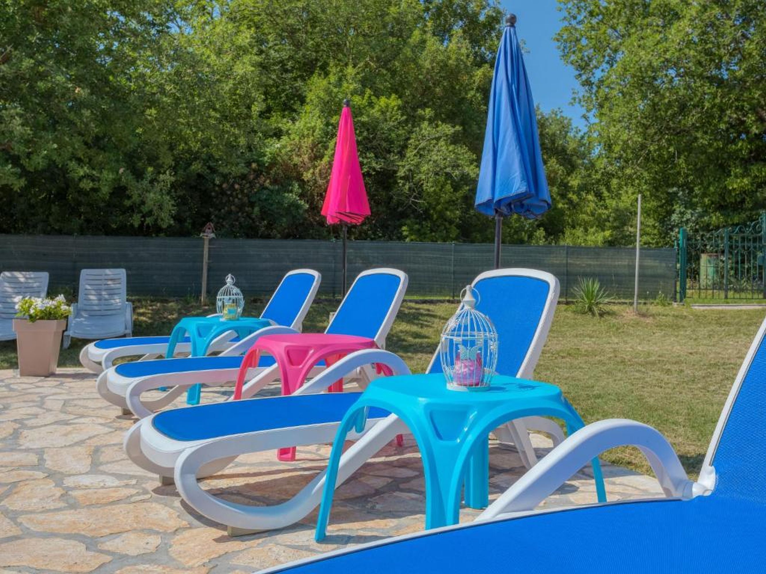 Outdoor lounge chairs with umbrellas, arranged on a stone patio.