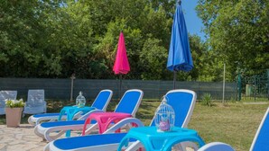 Outdoor lounge chairs with umbrellas, arranged on a stone patio. - House House Lola (Rasa)