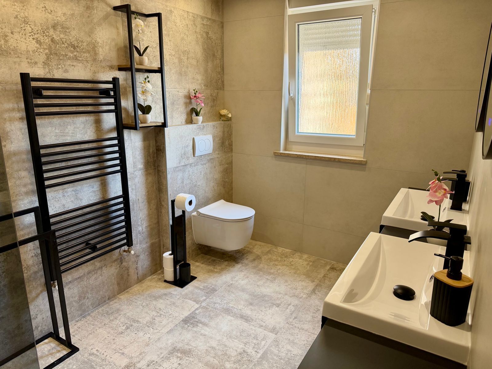 A bathroom with a toilet, a towel rack, a sink, and a window.