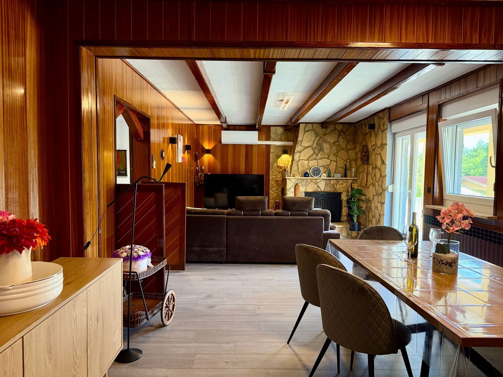 Ein gemütliches Wohnzimmer mit Kamin, Fernseher und einem Essbereich mit Stühlen und Tisch.
