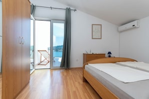 Ein Schlafzimmer mit Bett, Holzschrank, Schreibtisch mit Lampe und Blick durch eine Schiebetür.