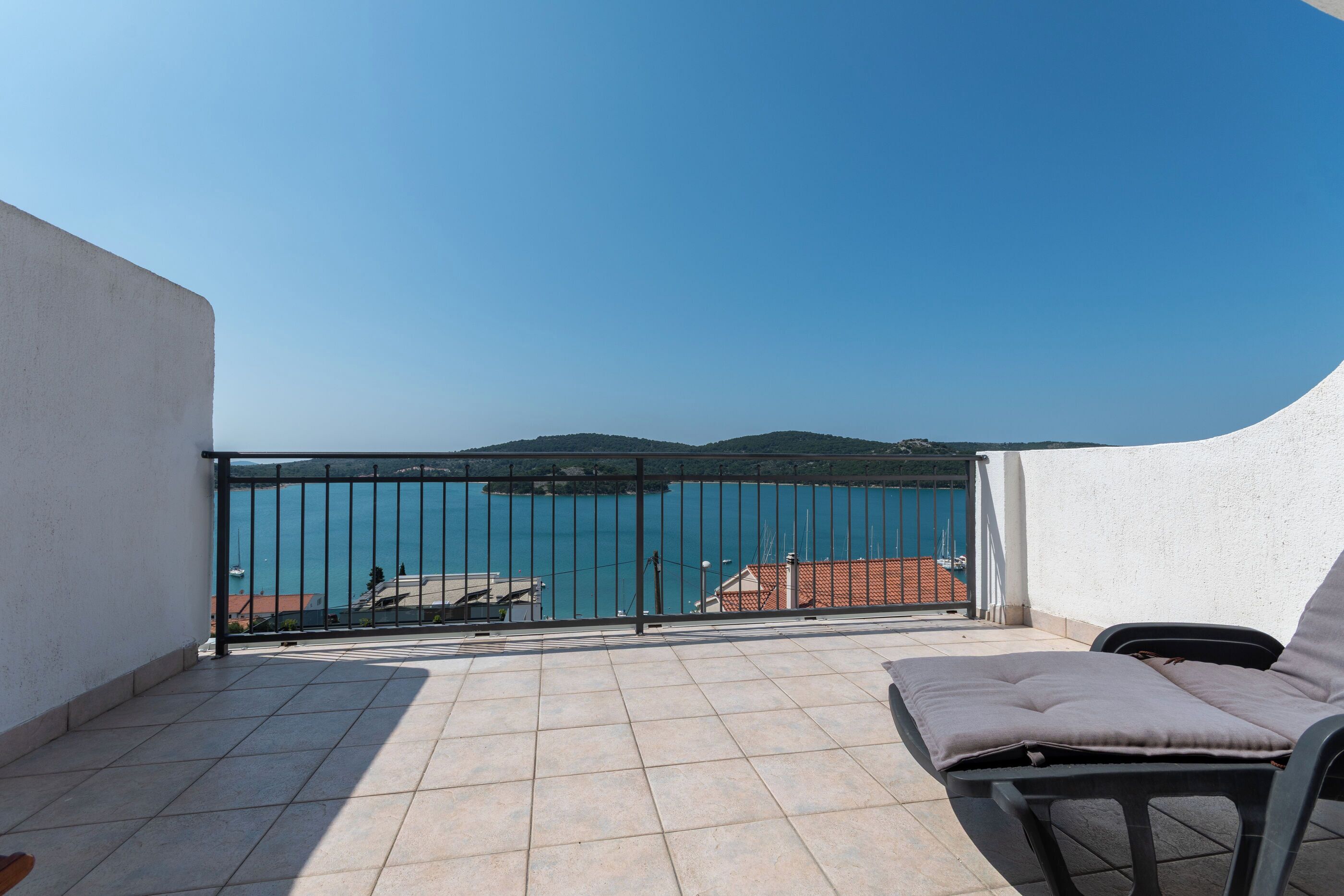 A balcony with a view of a body of water, a railing, and a chair.
