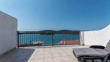 A balcony with a view of a body of water, a railing, and a chair.
