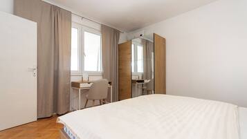 A bedroom with a bed, a desk, a chair, and a wardrobe.