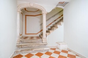 Eine Treppe mit Schachbrettboden, weißen Wänden und einer Tür am oberen Ende.